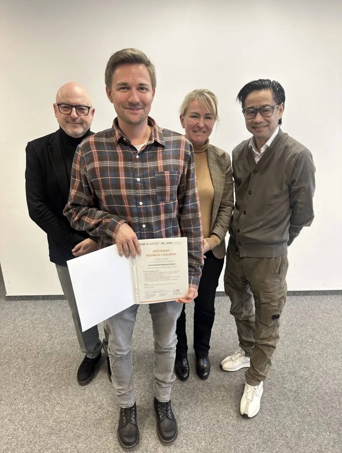 Absolvent der HM-i Business Coach Ausbildung mit Zertifikat, dahinter Dr. Peter Höher, Katharina Reischenbacher und Daisuke Motoki (ISM)