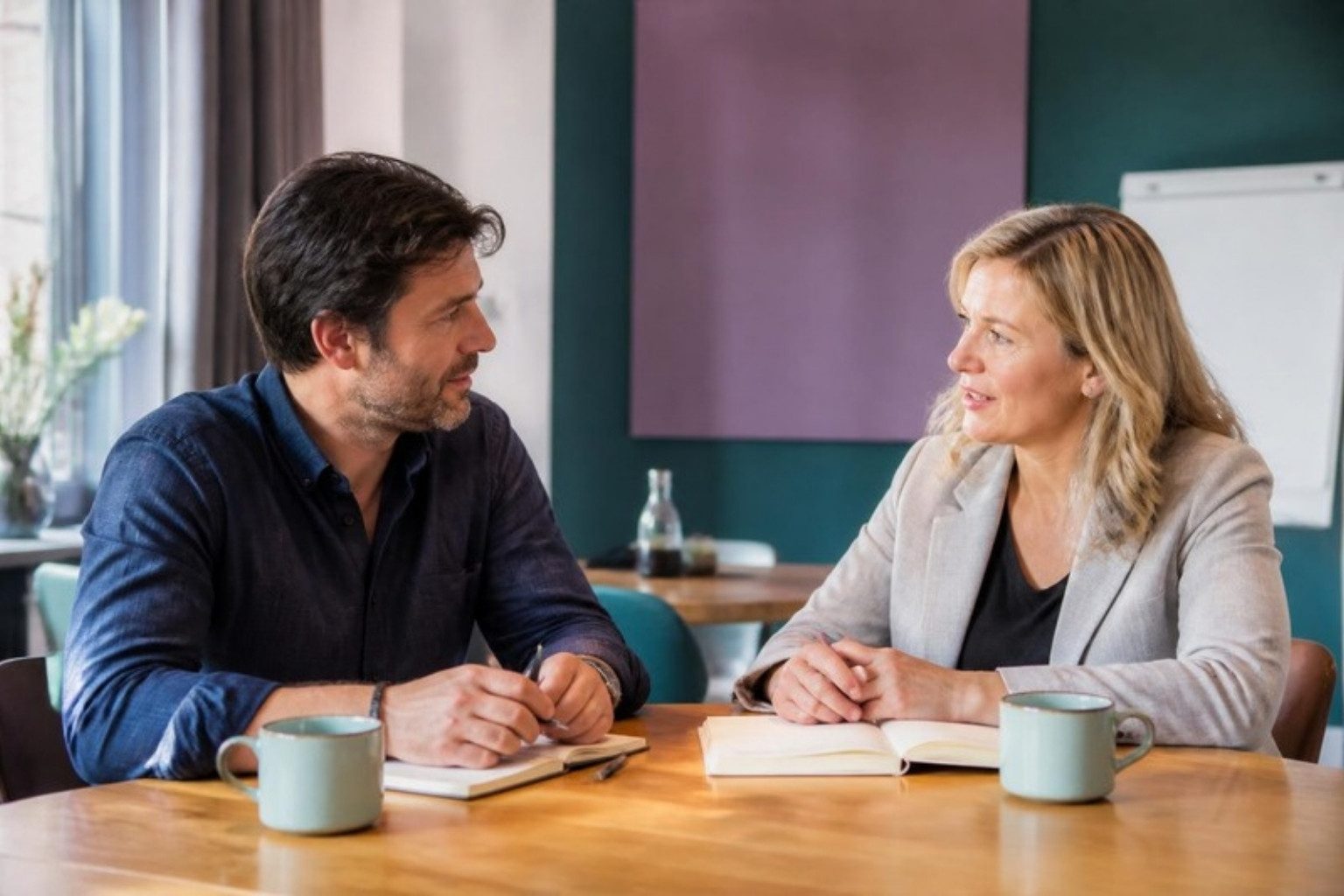 Business-Coaching-Gespräch am Tisch: Coachin und Klient im Austausch